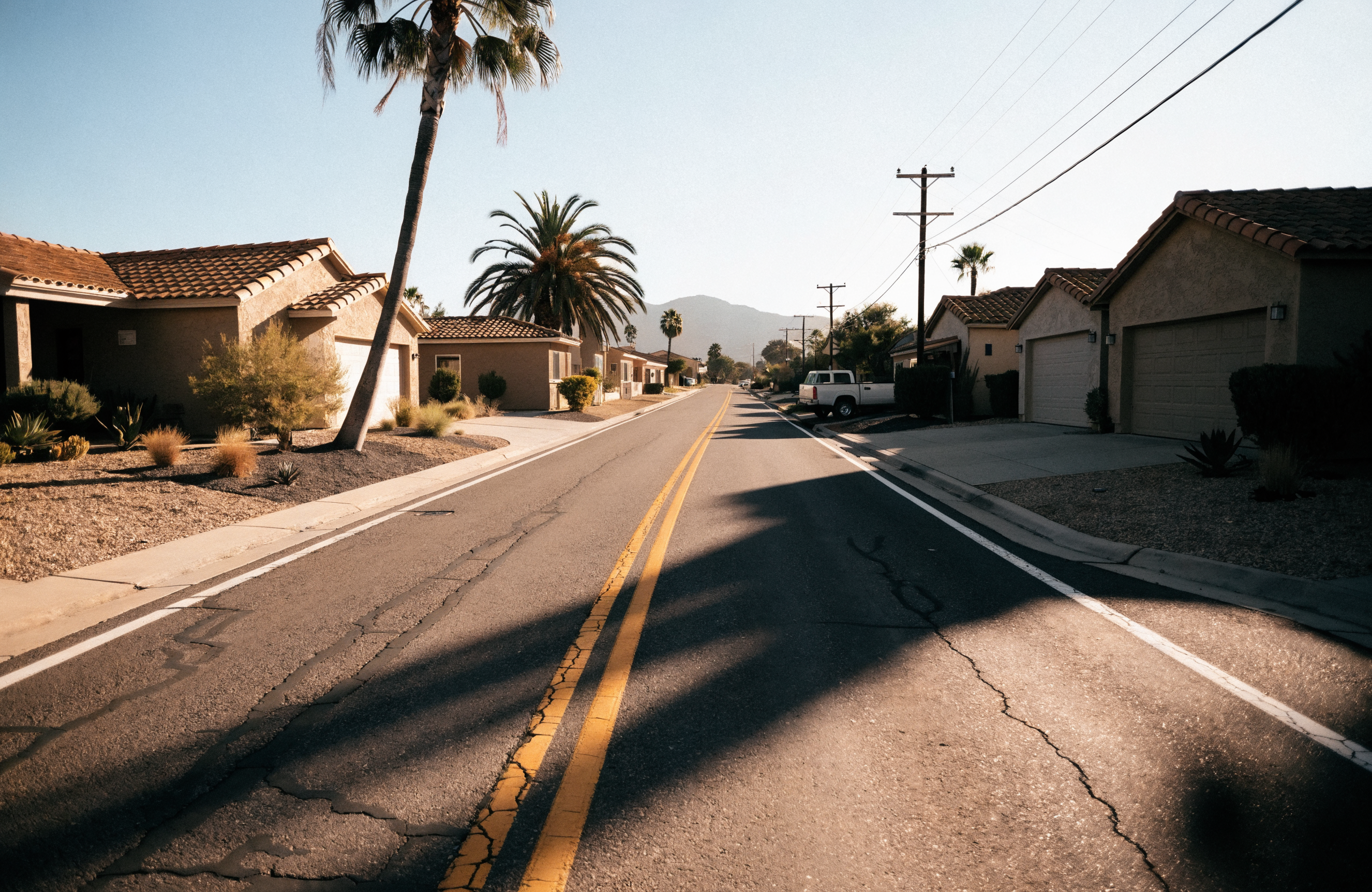 Suburban Southern California street with single-storey homes and a white service truck parked at the kerb