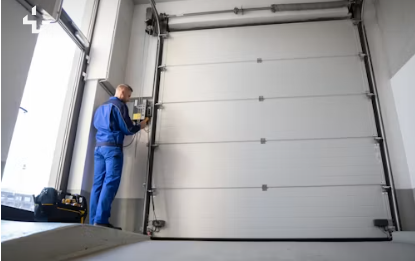 garage-door-tech-opener Technician servicing a commercial garage door opener mechanism, industrial setting